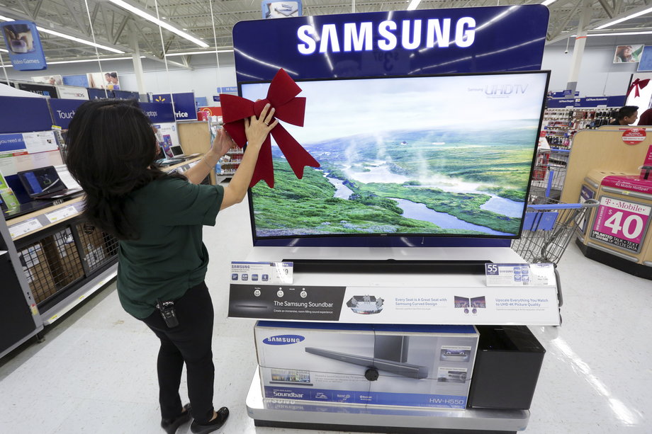 An employee adjusting a large ribbon on a television display at Walmart in preparation for Black Friday in Los Angeles in 2014.