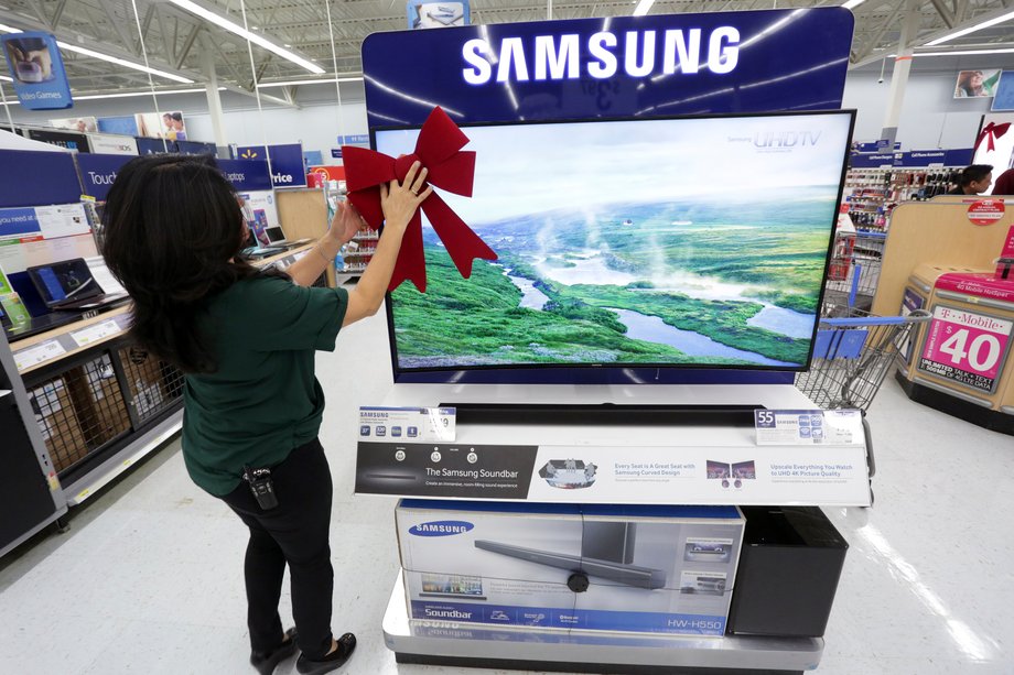 An employee adjusting a large ribbon on a television display at Walmart in preparation for Black Friday in Los Angeles in 2014.