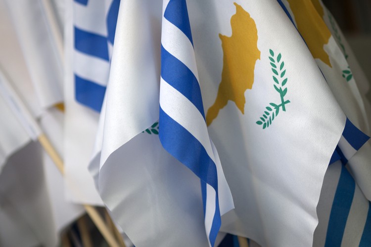 Rozwiązanie zastosowane na Cyprze w wielu kwestiach jest zbieżne z tym, co obecnie proponuje się Grecji. Ta propozycja to dalsza pomoc za obietnicę reform. Sytuację obu państw różni jednak szczegół. W 2013 r. na Cyprze pozwolono upaść lokalnym bankom, a nawet drugiemu co do wielkości pożyczkodawcy – Laiki. Akcjonariusze, obligatariusze oraz deponenci, których wkład wynosił więcej niż 100 tys. euro, stracili swoje pieniądze, ale państwo nie zostało obciążone tymi zobowiązaniami.

Na ten ruch zdecydowano się głównie ze względu na fakt, że sektor bankowy był wielokrotnie większy, niż wynikałoby to z rozmiarów gospodarki. To z kolei był efekt liberalnego podejścia lokalnych władz do pochodzenia pieniędzy oraz niskich podatków. Z tych powodów Cypr przyciągał kapitał zarówno ze wschodu, jak i z zachodu kontynentu.

W Grecji ten problem jest marginalny, jednak zagrożenie wariantem cypryjskim, protestami ulicznymi czy też wprowadzeniem kontroli przepływu kapitału może być dobrym „straszakiem” dla rządzącej, populistycznej Syrizy. Na fot. flagi Grecji i Cypru. Nikozja, Cypr, 19.03.2013