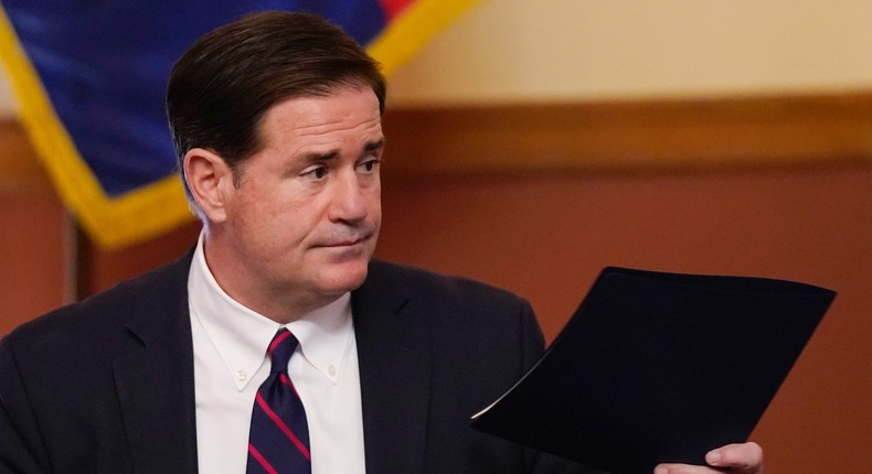 In this Nov. 30, 2020 file photo, Arizona Gov. Doug Ducey hands over his signed election documents to certify the election results for federal, statewide, and legislative offices and statewide ballot measures at the official canvass at the Arizona Capitol in Phoenix.
