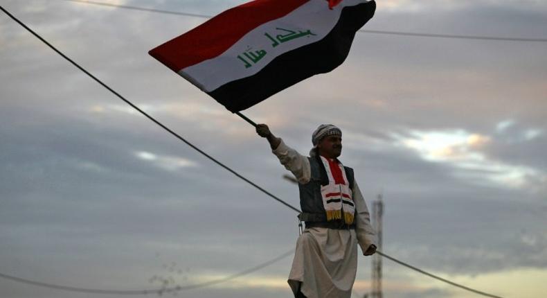 An Iraqi man waves his national flag in Baghdad's Tahrir Square on December 10, 2017, during a gathering celebrating the end of the three-year war against the Islamic State (IS) group