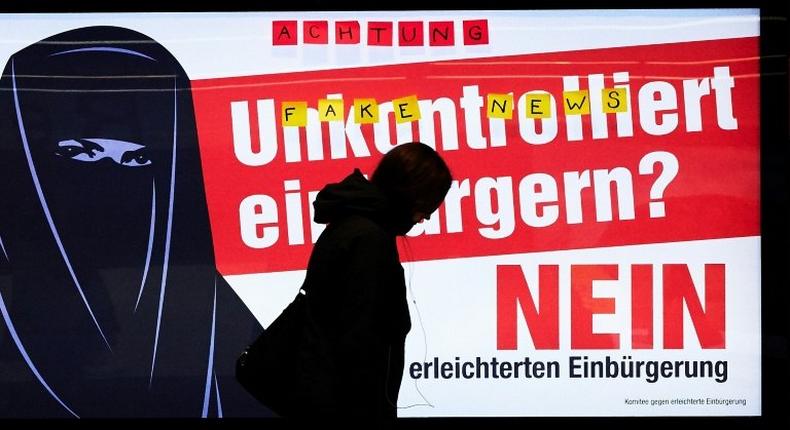 A man walks past an electoral poster by the Committee against Facilitated Naturalization/Citizenship reading Uncontrolled Naturalisation? No featuring a woman wearing a niqab, in a train station in Zurich, on February 7, 2017