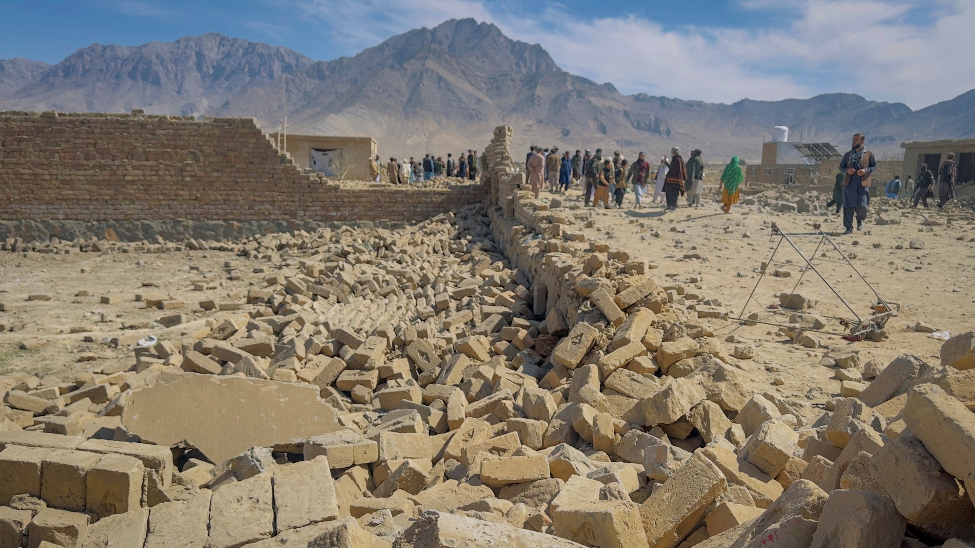 Ľudia stoja v blízkosti domu poškodeného pri nálete na predmestí Kábulu