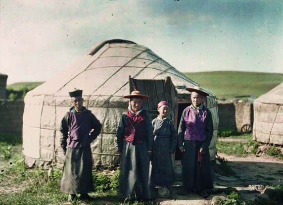 Chiny, region Mongolia Wewnętrzna. Trzej mężczyźni i chłopiec stoją przed tradycyjnym namiotem – jurtą (fot. Stéphane Passet, lipiec 1912, domena publiczna).