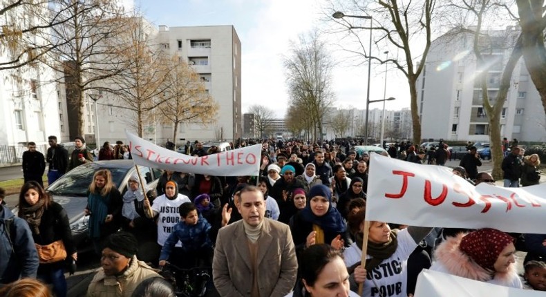 People holding signs reading Justice for Theo march through Aulnay-sous-Bois, north of Paris