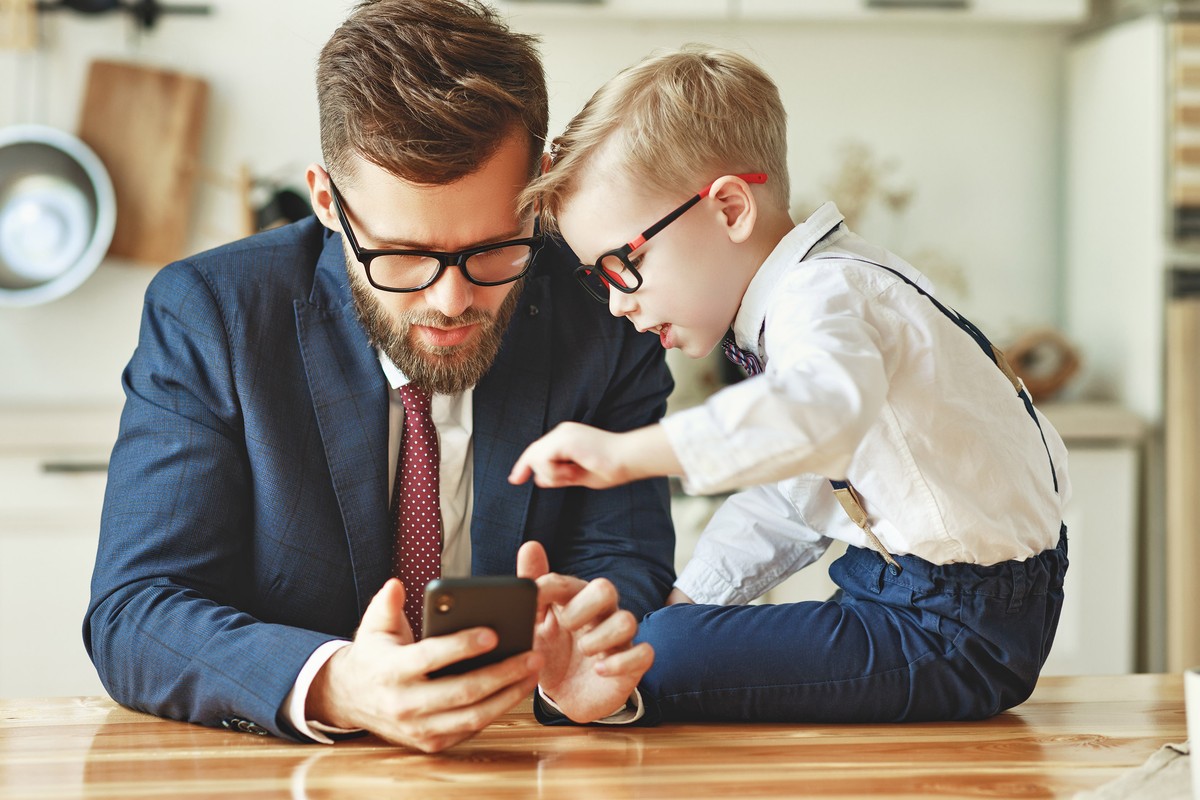 a businessman father with a young schoolboy son uses a smartphone