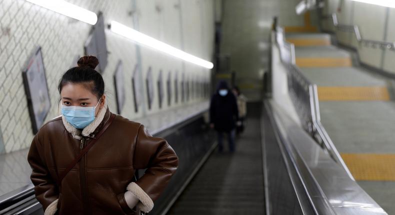 A woman wearing a face mask rides an escalator at an underpass leading to a subway station in the morning after the extended Lunar New Year holiday caused by the novel coronavirus outbreak, in Beijing, China February 10, 2020.  REUTERS/Carlos Garcia Rawlins