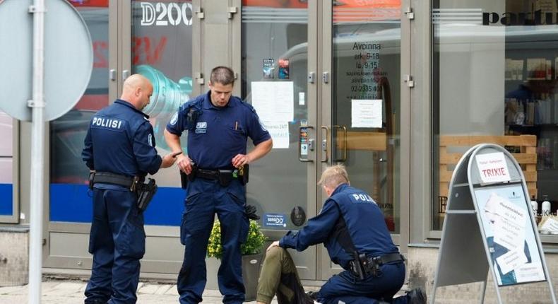 Police officers stand next to a person lying on the pavement in the Finnish city of Turku where several people were stabbed on August 18