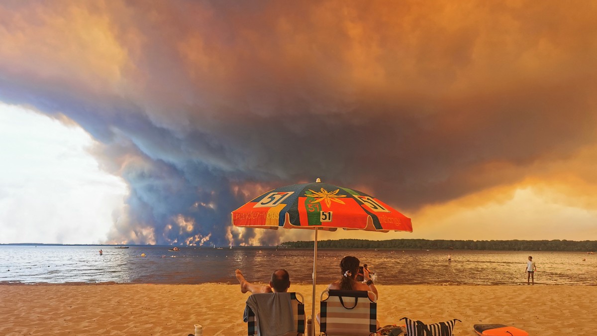 Posetioci plaže odmaraju se na plaži Mučik na obali jezera Lakano u Lakanou, na jugozapadu Francuske, dok požar besni u Žirondi, 24. jul 2026.