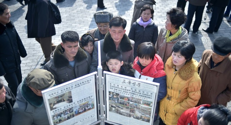 People in Pyongyang gather to read a copy of the Rodong Sinmun newspaper showing coverage of North Korea's leader Kim Jong Un arriving in Vietnam ahead of a Hanoi summit with US President Donald Trump