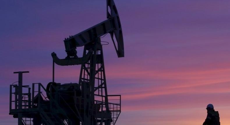 A worker walking past a pump jack on an oil field owned by Bashneft, Bashkortostan