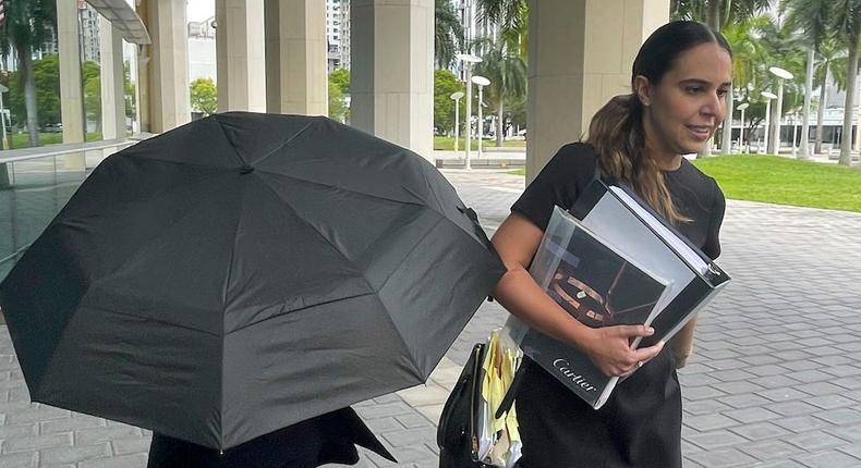 Handbag designer Nancy Gonzalez hides under an umbrella as she walks with her lawyer outside the federal courthouse, April 22, 2024, in Miami.Josh Goodman/AP Photo