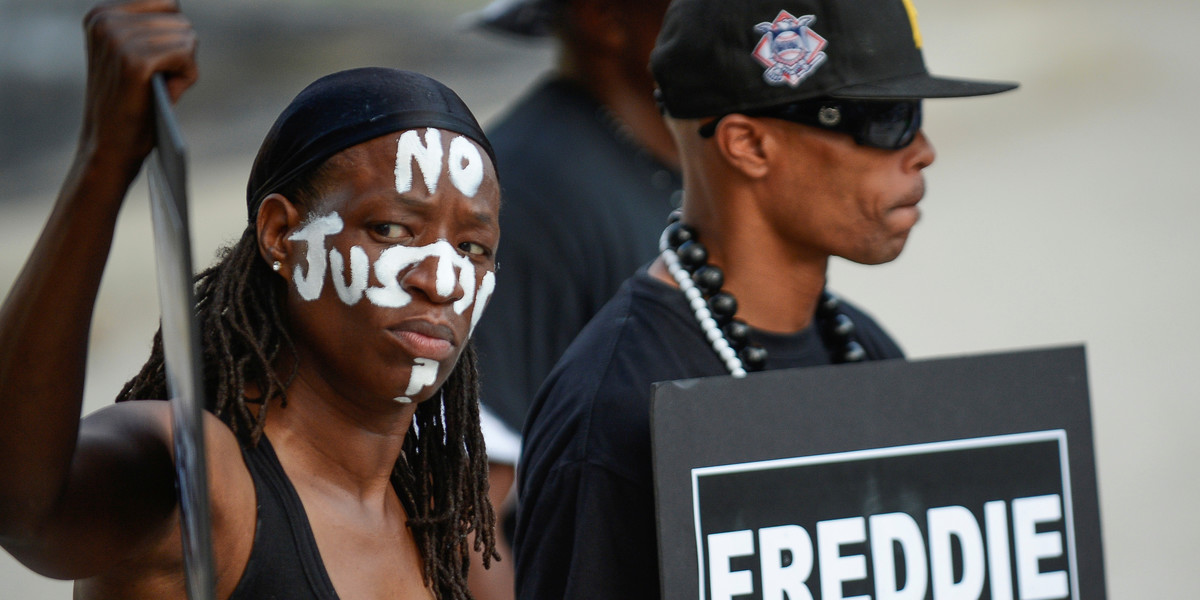 Angel Selah, left, and local artist PFK Boom gather to remember Freddie Gray and all victims of police violence during a rally outside city hall in Baltimore, Maryland, July 27, 2016.