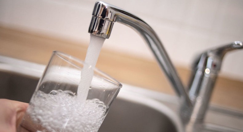 A man holds a glass under a running tap.