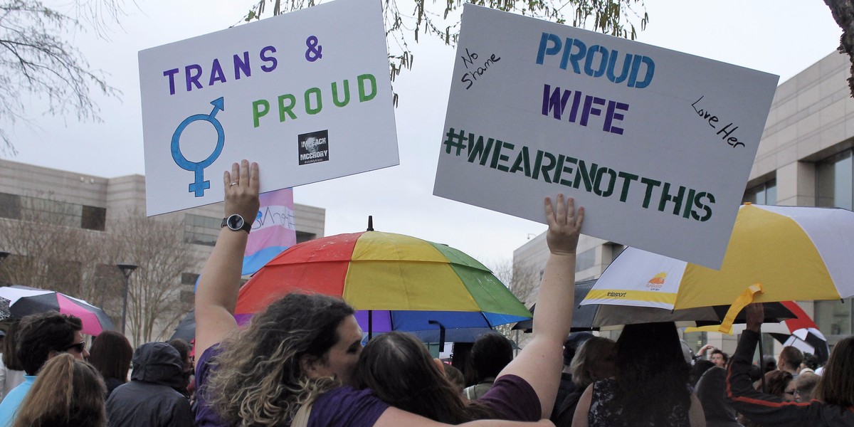 Two protesters with signs against passage of legislation in North Carolina that limits the bathroom options for transgender people.