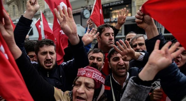 Protesters shout slogans and wave Turkish national flags in front of the Dutch Consulate in Istanbul on March 12, 2017