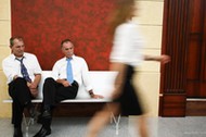 Two businessmen looking at woman's legs