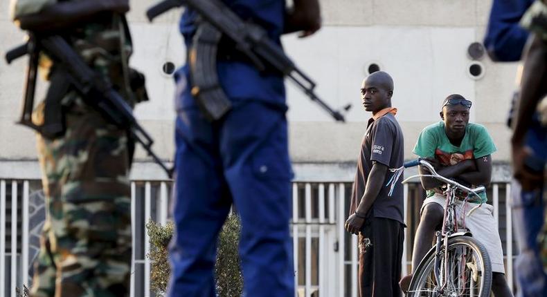 Residents look on as police and soldiers guard a voting station in Burundi's capital Bujumbura during the country's presidential elections, July 21, 2015.   REUTERS/Mike Hutchings