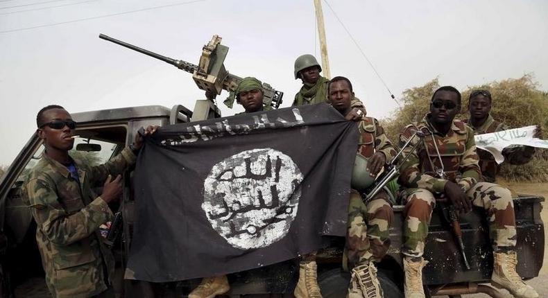 Nigerian soldiers hold up a Boko Haram flag that they had seized in the recently retaken town of Damasak, Nigeria, March 18, 2015. 