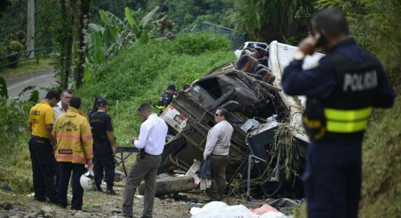 Policemen and rescue officials check the site where a bus plunged off a steep road killing 11 and injuring 12 in Heredia, Vara Blanca, Costa Rica on October 20, 2016