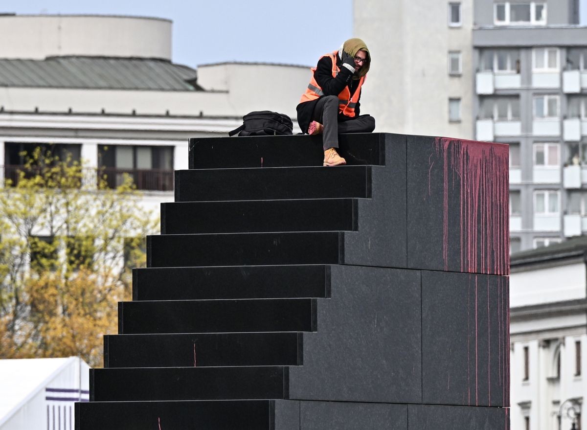 Aktywista Ostatniego Pokolenia na Pomniku Ofiar Tragedii Smoleńskiej 2010 roku na pl. Piłsudskiego w Warszawie