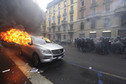 Italian anti-riot policemen run in front of a burning car during a rally against Expo 2015 in Milan