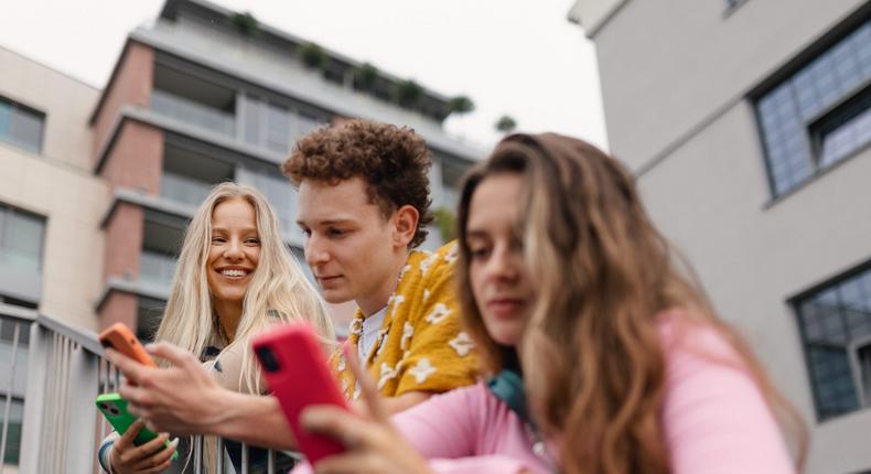 A girl looks to her friends as they look at their phonesHalfpoint/Getty Images