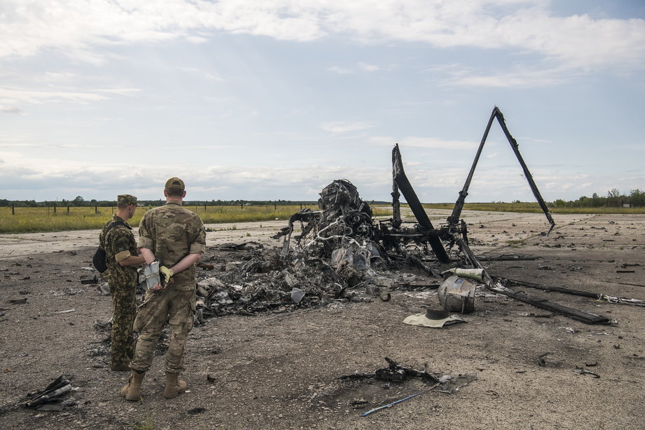 Ukraińscy żołnierze patrzą na fragmenty rosyjskiego wojskowego Ka-52 Aligator Helikopter zniszczony przez armię ukraińską podczas rosyjskiej inwazji na Ukrainę na lotnisku Hostomel pod Kijowem na Ukrainie. 8 lipca 2022 r.