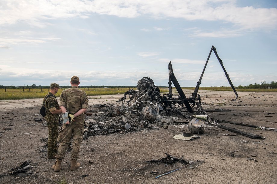 Ukraińscy żołnierze patrzą na fragmenty rosyjskiego wojskowego Ka-52 Aligator Helikopter zniszczony przez armię ukraińską podczas rosyjskiej inwazji na Ukrainę na lotnisku Hostomel pod Kijowem na Ukrainie. 8 lipca 2022 r.