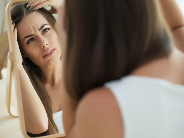 Kobieta ogląda swoje włosy w lustrze