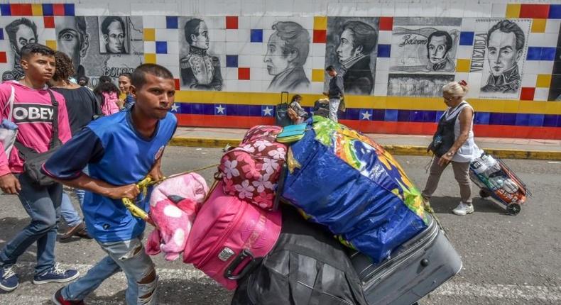 Thousands of Venezuelans, many hauling overloaded suitcases, cross the border into Colombia to escape unrest and penury at home