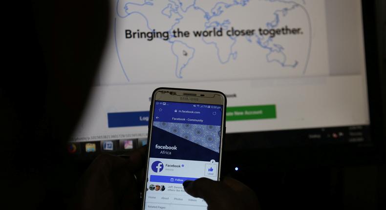 An illustration photo shows the Facebook page displayed on a mobile phone internet browser held in front of a computer screen at a cyber-cafe in downtown Nairobi