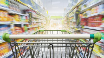 Supermarket aisle with empty green shopping cart