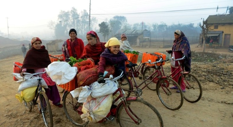 Female vendors, using their bicycles to carry their vegetables, arrive to sell their wares at a market in Nepal this February