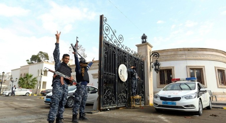 Libyan security forces flash victory signs outside the Guest Palace, a complex of luxury villas in central Tripoli on March 15, 2017