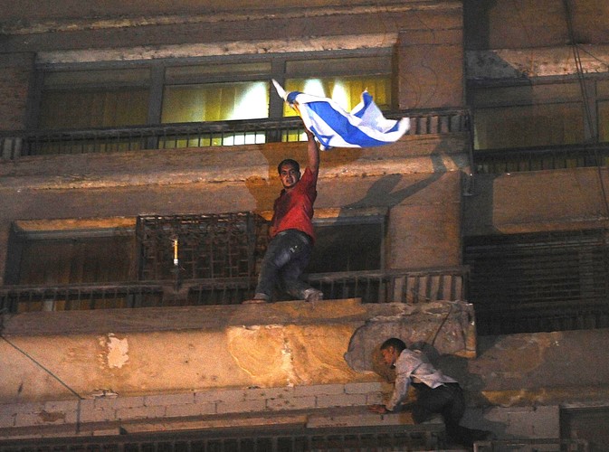 Jeden z protestujących zrywa izraelską flagę z budynku ambasady