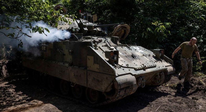 A soldier from Ukraine's 47th Mechanized Brigade runs past a US-made Bradley Fighting Vehicle as the engine is started at a secret workshop in a wooded area in the southern Zaporizhzhia Region.Ed Ram/For The Washington Post via Getty Images