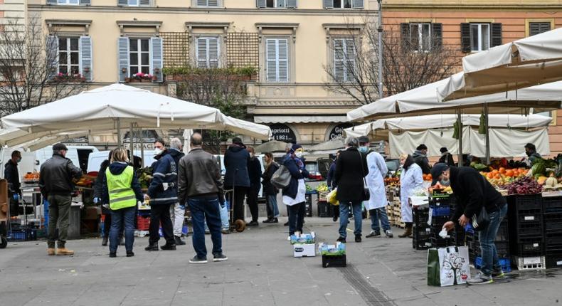 A municipal policeman checks people are keeping their distance at the fruit and vegetable market in piazza San Cosimato, in the Rome district district of Trastevere