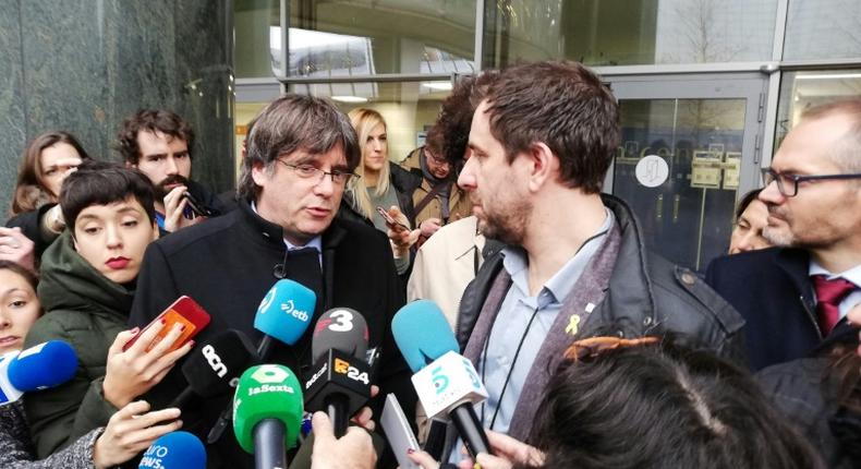 Former Catalan regional president Carles Puigdemont (C-L) and his health minister Toni Comin (C-R) talk to the press after receiving their badges as accredited members of the European Parliament on December 20, 2019 in Brussels