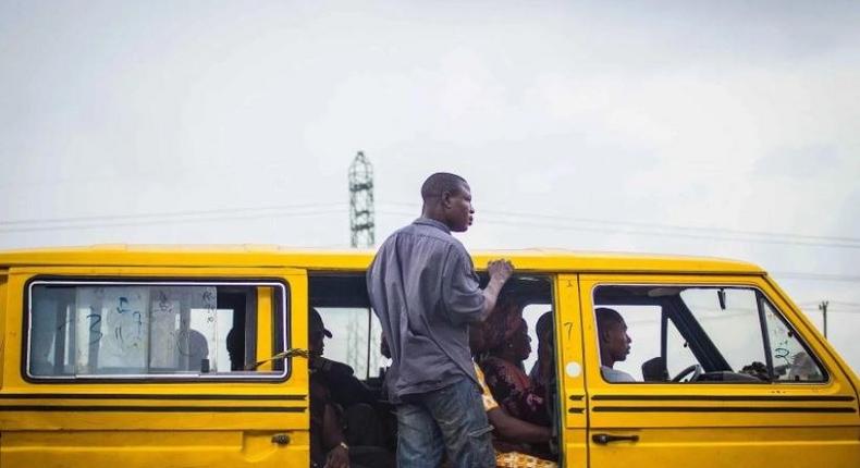 A Lagos 'Danfo' conveying people to their destination, 'Agbero' helps the driver.