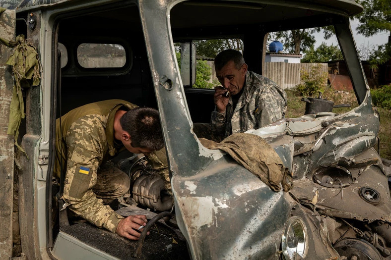 Żołnierze demontujący porzucony rosyjski pojazd.