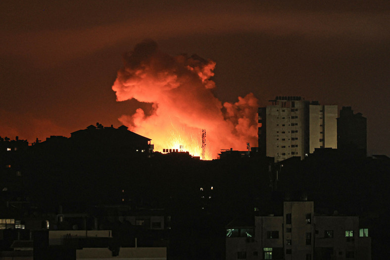 Ogień i dym unoszące się nad budynkami w Strefie Gazy podczas izraelskiego nalotu, 13 października 2023 r.