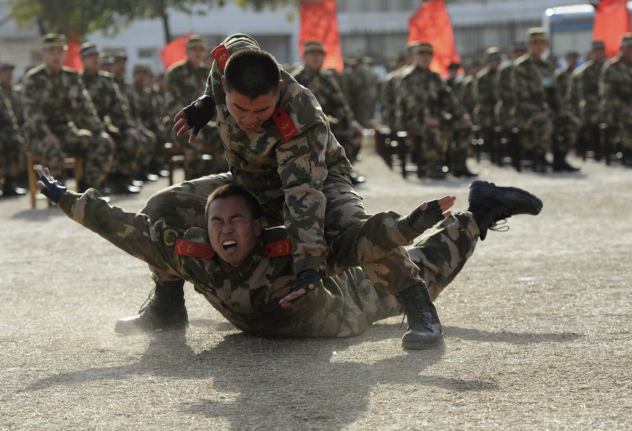 Paramilitary policemen take part in an unarmed combat demonstration for the new recruits (background) at a military base in Hefei, Anhui province, China.