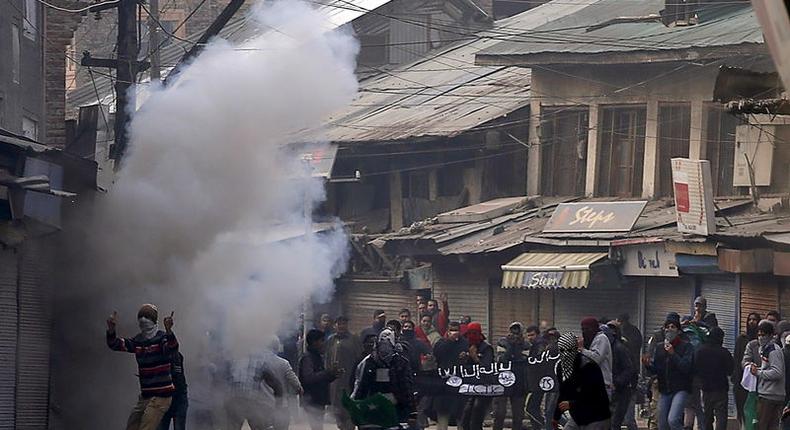 Kashmiri protesters hold a banner similar to the flag commonly used by Islamic State bearing the acronym ISJK, which stands for Islamic State and Jammu Kashmir, amid smoke of tear gas fired by Indian police during a protest in Srinagar, November 20, 2015. REUTERS/Danish Ismail