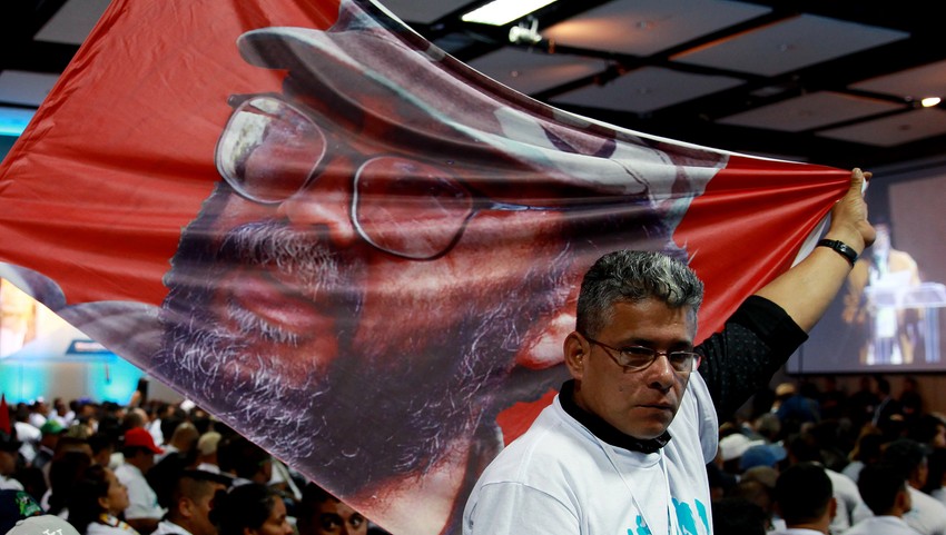 Pristalica FARK-a nosi zastavu sa slikom pokojnog lidera Giljerma Leona Saensa, poznato kao "'Alfonso Kano"