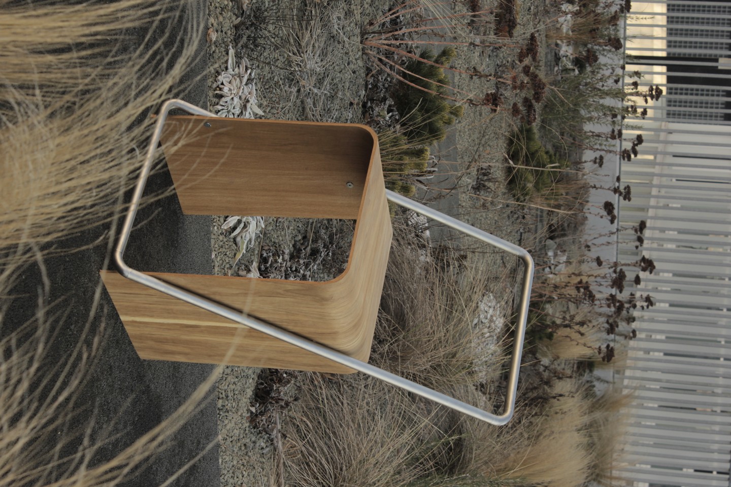 Nagy Karola: UDØ. A tárgy a finom formai harmóniát intelligens szerkezettel ötvözi. A hajlított tölgy rétegelt lemez és a körbefutó rozsdamentes acél háttámla-lábtartó párosa izgalmas anyagtársítást és formai kísérletet hoz létre