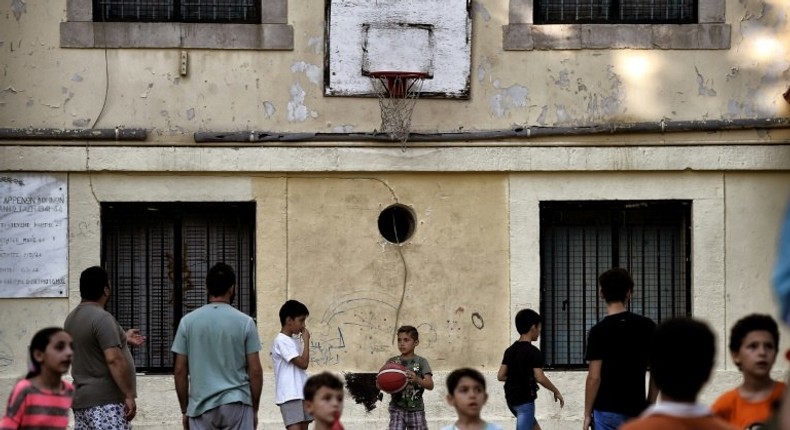 Children play in the courtyard of an abandoned school used to host Syrian and Afghan refugees in Athens on July 1, 2016