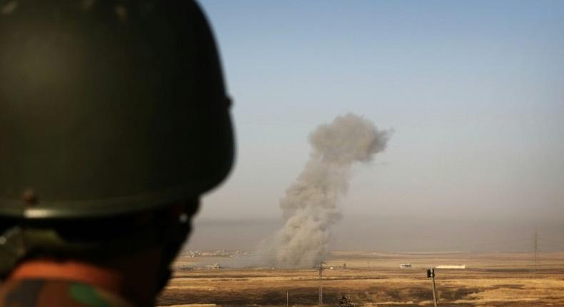 Smoke billows on the front line as an Iraqi Kurdish peshmerga fighter looks on from a position east of the city of Mosul