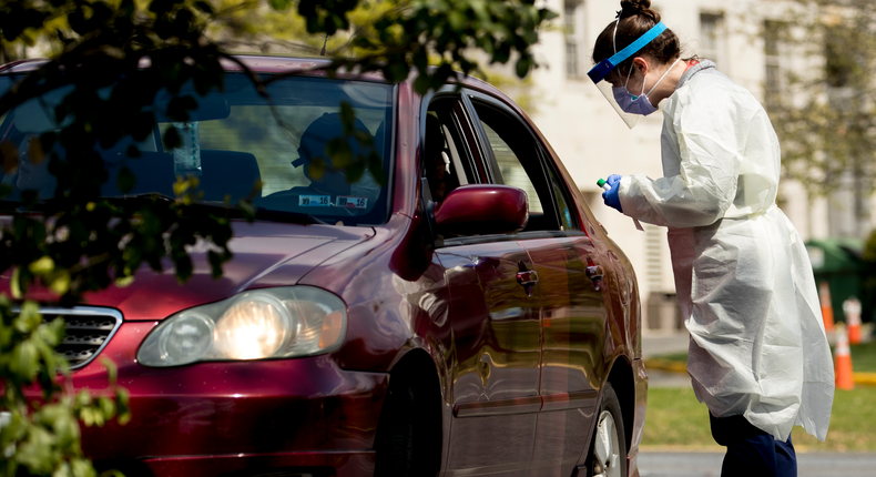 A medical worker prepares to test a young man for COVID-19 at a Children's National Hospital drive-through (drive-in) coronavirus testing site at Trinity University, Thursday, April 16, 2020, in Washington. (AP Photo/Andrew Harnik)