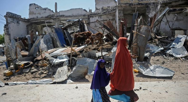 Local residents walk past the scene of a deadly December 22, 2018 car bomb attack in the Somali capital Mogadishu claimed by the jihadist group Shabaab